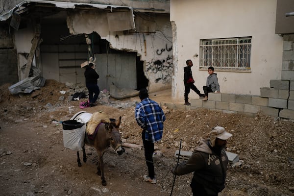 Locals stand next to a damaged building after the latest Israeli military operation, in the West Bank city of Tulkarem, Thursday, Dec. 26, 2024. (AP Photo/Matias Delacroix)