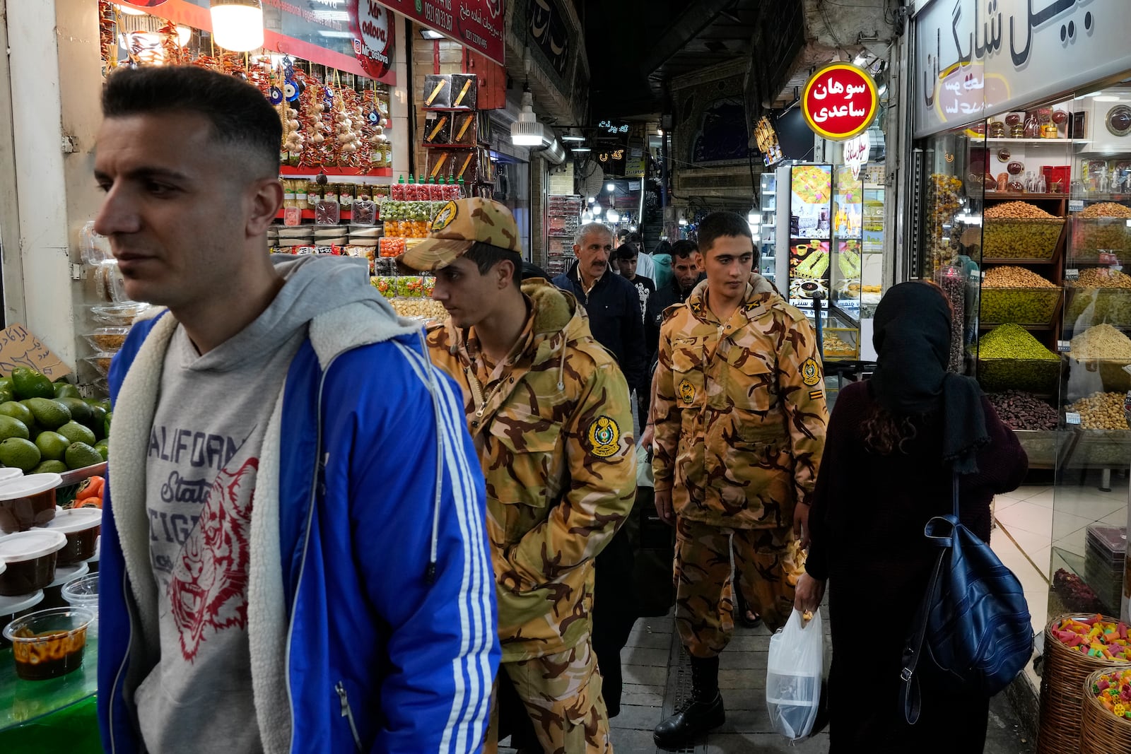 Two army soldiers and people walk through Tajrish traditional bazaar in northern Tehran, Iran, Saturday, Oct. 26, 2024. (AP Photo/Vahid Salemi)