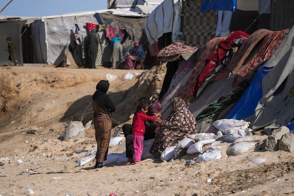 Palestinian families sit outside of tents made locally from pieces of cloth and nylon, in a camp for internally displaced Palestinians at the beachfront in Deir al-Balah, central Gaza Strip, Friday, Dec. 27, 2024. (AP Photo/Abdel Kareem Hana)