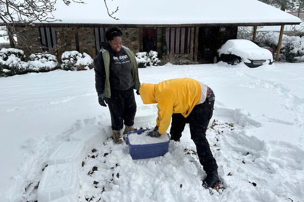 Tyshae Sanders and Terrell Bryant work on building an igloo using a plastic bucket in Little Rock, Ark., Friday, Jan. 10, 2025. (AP Photo/Andrew DeMillo)