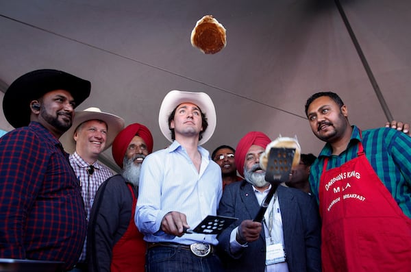 FILE - Liberal leader Justin Trudeau, center, flips pancakes at a Stampede breakfast in Calgary, Alta., on July 7, 2013. (Jeff McIntosh/The Canadian Press via AP, File)