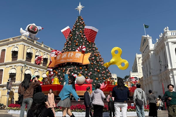 Mainland Chinese tourists take photos in front of a Christmas installation in Macao's historic Senado Square on Dec. 13, 2024. (AP Photo/Kanis Leung)