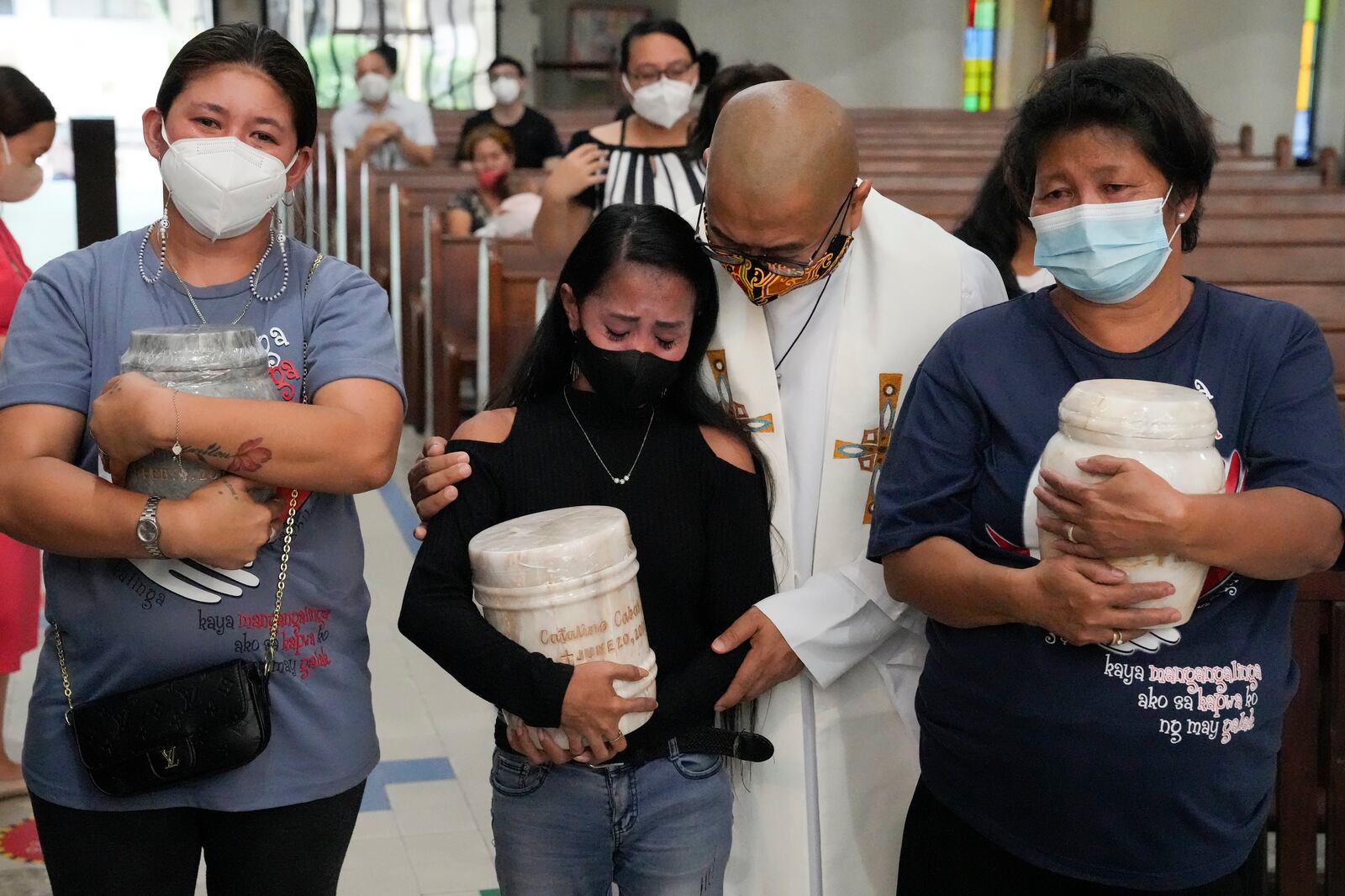 FILE - Catholic priest Flaviano "Flavie" Villanueva comforts relatives as they receive the urns containing the remains of victims of alleged extrajudicial killings of President Rodrigo Duterte's so-called war on drugs at a church in Quezon city, Philippines, Wednesday, Sept. 28, 2022. (AP Photo/Aaron Favila, File)