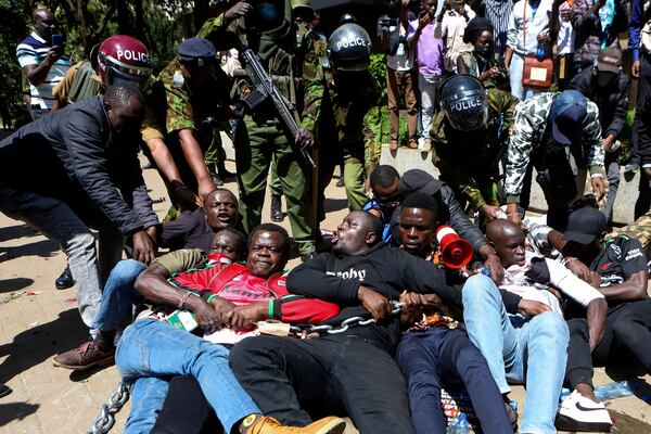 Police arrest protesters who have chained themselves during protests against abductions in Nairobi, Kenya, Monday, Dec. 30, 2024. AP Photo/Andrew Kasuku)