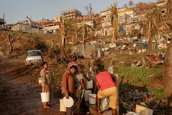 People line up to collect water in Barakani, Mayotte, home Saturday, Dec. 21, 2024. (AP Photo/Adrienne Surprenant)