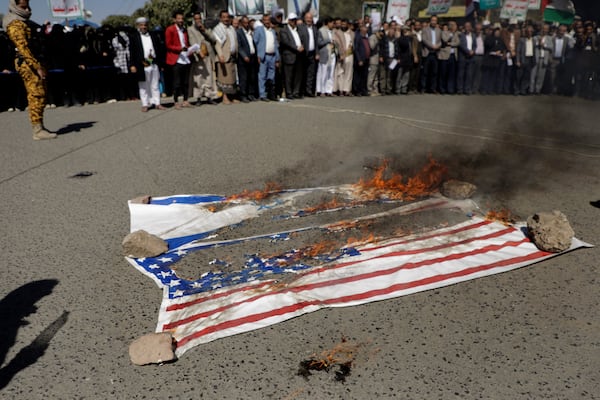 Houthi supporters burn American and Israeli flags during a protest in Sanaa, Yemen, Wednesday, Jan. 22, 2025. (AP Photo/Osamah Abdulrahman)