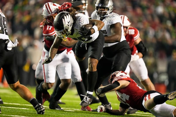 Oregon's Jordan James (20) is tripped up byWisconsin's Hunter Wohler (24) during the second half of an NCAA college football game Saturday, Nov. 16, 2024, in Madison, Wis. Oregon won 16-13. (AP Photo/Morry Gash)