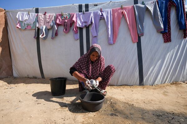 Fathia Abu Mansour, 51, displaced from Jabaliya, washes kitchen utensils outside her tent at a camp for displaced Palestinians in Deir al-Balah, Gaza Strip, on Nov. 7, 2024. (AP Photo/Abdel Kareem Hana)