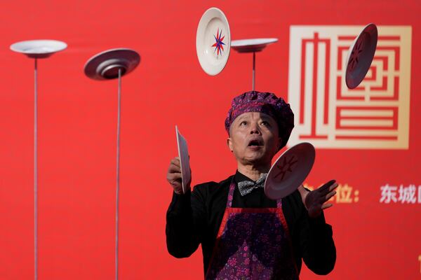 A performer juggles plates during a presentation at the crowded Ditan Temple Fair on the first day of the Chinese Lunar New Year in Beijing on Wednesday, Jan. 29, 2025. (AP Photo/Aaron Favila)