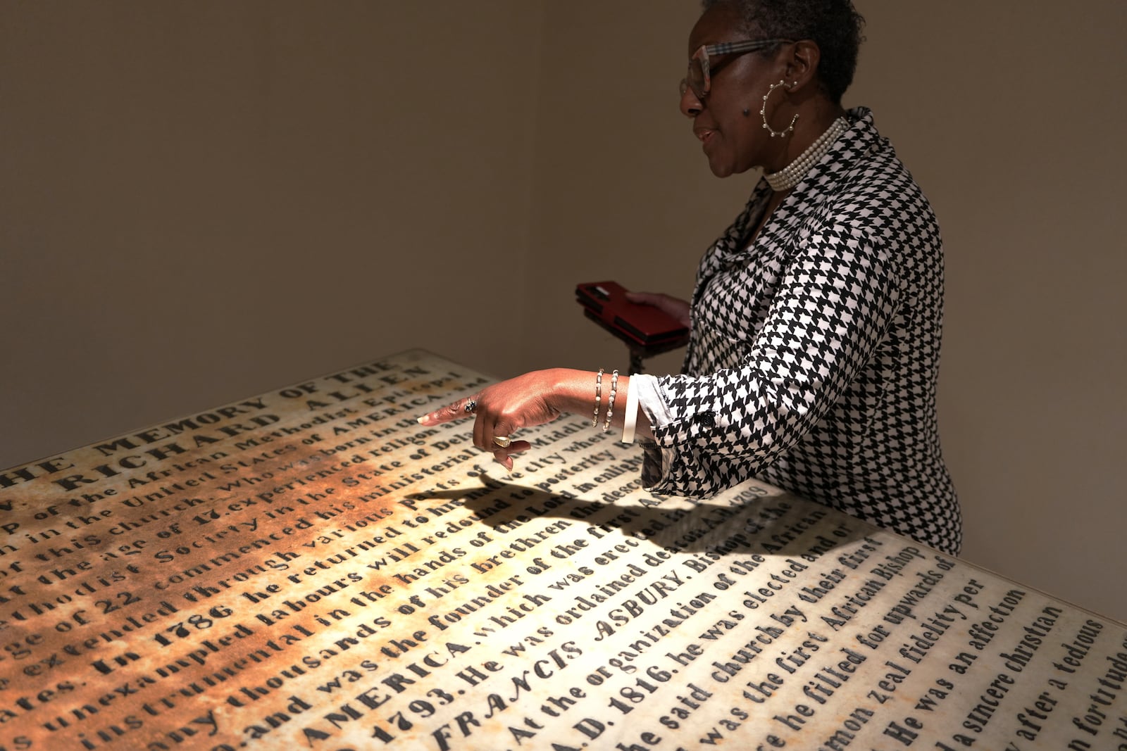 Mother Bethel AME Church member, Wanda Davis, points to the tomb of the church’s founder, the Rev. Richard Allen, at the church museum on Sunday, Sept. 29, 2024. (AP Photo/Luis Andres Henao)