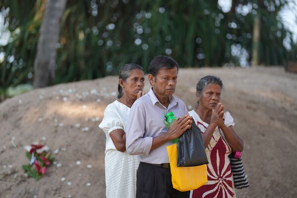 Relatives pray for their dead relatives in 2004 Indian Ocean tsunami, standing by a mass grave during a memorial of the 20th anniversary of the calamity in Peraliya, Sri Lanka, Thursday, Dec. 26, 2024. (AP Photo/Eranga Jayawardena)