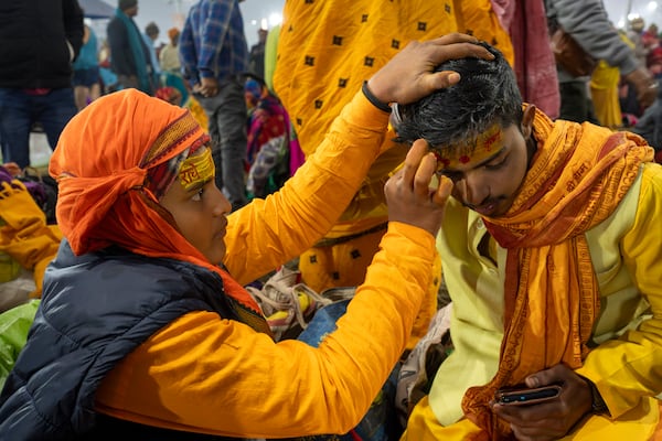 A Hindu devotee gets sacred marks painted on his forehead by a priest at the confluence of the Ganges, the Yamuna, and the Saraswati rivers on the first day of the 45-day-long Maha Kumbh festival in Prayagraj, India, Monday, Jan. 13, 2025. (AP Photo/Ashwini Bhatia)