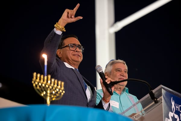 Jacob Monty joins Rabbi Peter Tarlow at the podium during a Chicanukah event at Holocaust Museum Houston on Thursday, Dec. 19, 2024, in Houston. (AP Photo/Annie Mulligan)