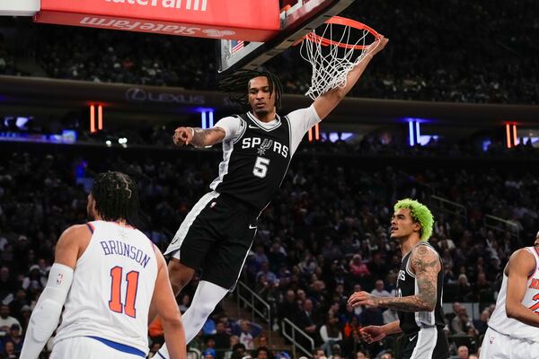 San Antonio Spurs' Stephon Castle, top, reacts after dunking the ball during the first half of an NBA basketball game against the New York Knicks, Wednesday, Dec. 25, 2024, in New York. (AP Photo/Seth Wenig)