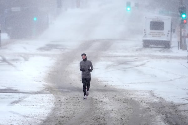 A person who declined to be identified jogs down a snow-covered street Sunday, Jan. 5, 2025, in St. Louis. (AP Photo/Jeff Roberson)