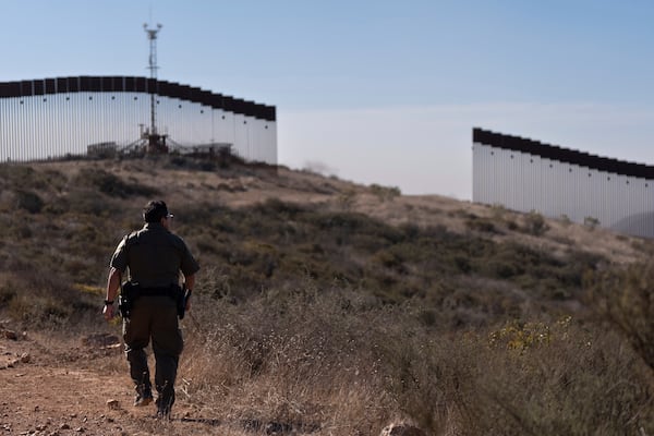 Border Patrol Agent Gutierrez walks towards a gap in one of two border walls separating Mexico from the United States, Thursday, Jan. 23, 2025, in San Diego. (AP Photo/Gregory Bull)