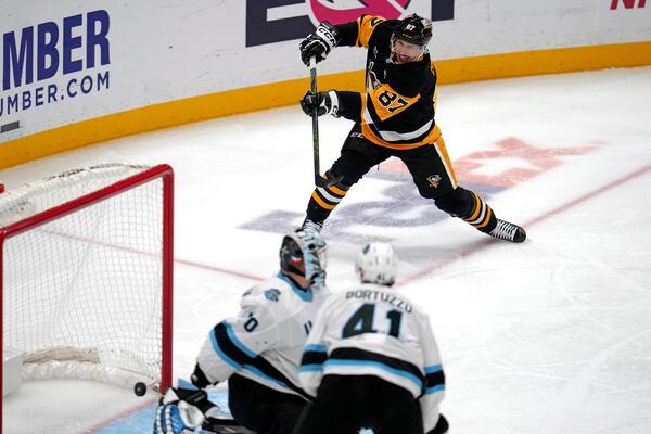 Pittsburgh Penguins' Sidney Crosby (87) gets a shot behind Utah Hockey Club goaltender Karel Vejmelka (70) for his 600th career goal in the NHL during the second period of an NHL hockey game Saturday, Nov. 23, 2024, in Pittsburgh. (AP Photo/Gene J. Puskar)