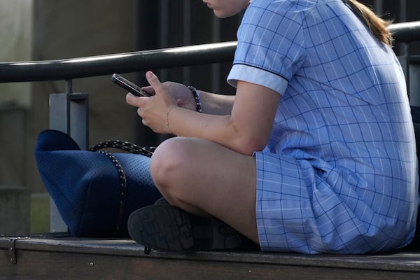 A young girl uses her phone while sitting on a bench in Sydney, Friday, Nov. 8, 2024. (AP Photo/Rick Rycroft)