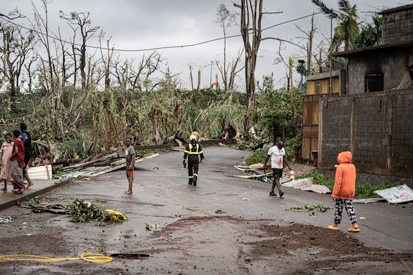 This photo provided on Monday Dec. 16, 2024 by the Civil Security shows residents and rescue workers walking in a damaged street in French territory of Mayotte in the Indian Ocean, after the island was battered by its worst cyclone in nearly a century. (UIISC7/Securite Civile via AP)