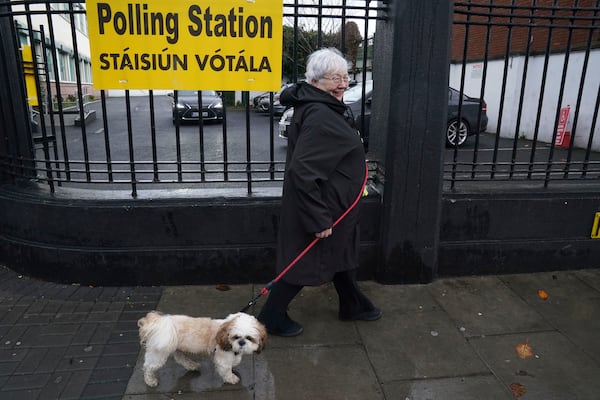 A woman and her dog leaves after voting at the polling station at St Laurence O'Tooles National School in Dublin, Friday Nov. 29, 2024, as voters go to the polls in the 2024 General Election in Ireland. (Brian Lawless/PA via AP)