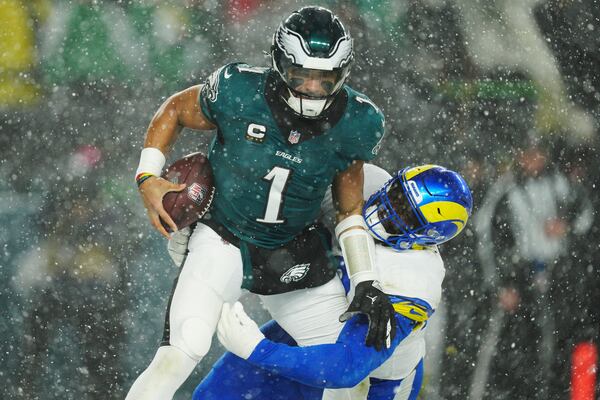 Los Angeles Rams defensive tackle Neville Gallimore (92) tackles Philadelphia Eagles quarterback Jalen Hurts (1) during the second half of an NFL football NFC divisional playoff game Sunday, Jan. 19, 2025, in Philadelphia. (AP Photo/Derik Hamilton)