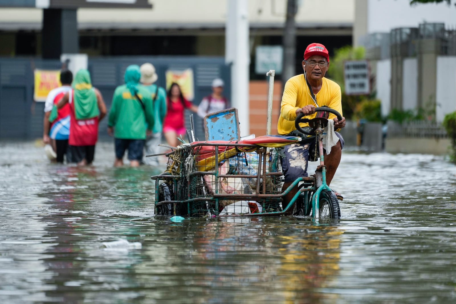 A man navigates flooded streets caused by Tropical Storm Trami on Friday, Oct. 25, 2024, in Cainta, Rizal province, Philippines. (AP Photo/Aaron Favila)