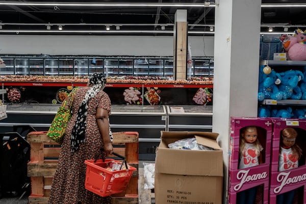 A woman looks at empty freezers as she looks for food supplies in Mamoudzou, Mayotte, Thursday, Dec. 19, 2024 (AP Photo/Adrienne Surprenant)