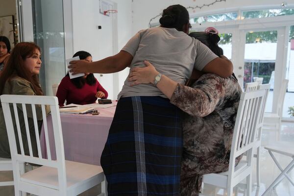 A mother thanks notary Adela Morales, right, and Nora Sandigo, left, after she signed documents giving Sandigo legal guardianship of her children, Sunday, Jan. 19, 2025, in Miami. Since December, Sandigo has become the legal guardian of at least 30 children. She has been doing so for 15 years and is the legal guardian to more than 2,000 children of undocumented immigrants. (AP Photo/Marta Lavandier)