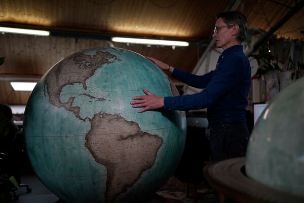 FILE - Peter Bellerby, the founder of Bellerby & Co. Globemakers, holds a globe at a studio in London, Tuesday, Feb. 27, 2024. (AP Photo/Kin Cheung, File)