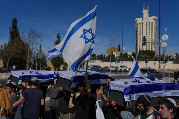 Activists representing families of Israelis killed during the war in Gaza carry mock coffins covered with Israeli flags that are meant to symbolize the price Israel will pay for agreeing to a ceasefire with Hamas in a demonstration against the deal , in Jerusalem on Thursday, Jan. 16, 2025. (AP Photo/Ohad Zwigenberg)