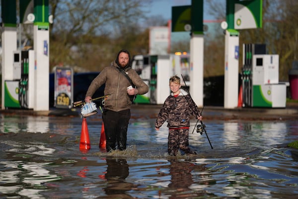 People walk through floodwater near the Billing Aquadrome in Northamptonshire, England, Monday Nov. 25, 2024, after Storm Bert caused "devastating" flooding over the weekend. (Jordan Pettitt/PA via AP)