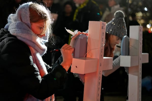 Supporters sign crosses during a candlelight vigil Tuesday, Dec. 17, 2024, outside the Wisconsin Capitol in Madison, Wis., following a shooting at the Abundant Life Christian School on Monday, Dec. 16. (AP Photo/Morry Gash)