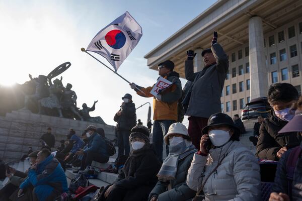 A protester waves a South Korean flag as he joins others gathering outside the National Assembly in Seoul, South Korea, Wednesday, Dec. 4, 2024. (AP Photo/Ng Han Guan)