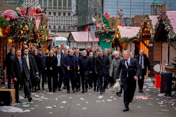 German Chancellor Olaf Scholz, centre, walks over a Christmas Market, where a car drove into a crowd on Friday evening, in Magdeburg, Germany, Saturday, Dec. 21, 2024. (AP Photo/Michael Probst)