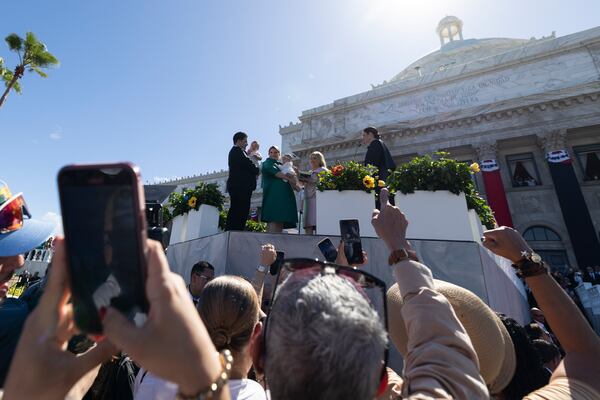 Jenniffer Gonzalez Colon and her husband hold their children on a podium outside the Capitol during Colon's swearing-in ceremony as governor in San Juan, Puerto Rico, Thursday, Jan. 2, 2025. (AP Photo/Alejandro Granadillo)