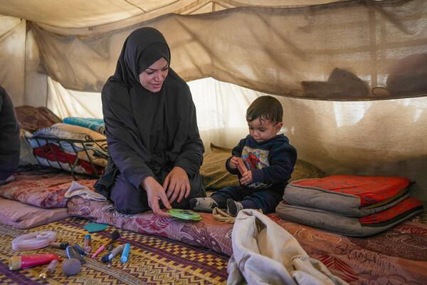 Alaa Hamami shows her cosmetics while playing with her 8-month-old son Ahmed inside their tent at a camp for displaced Palestinians in Deir al-Balah, Gaza Strip, Dec. 18, 2024. (AP Photo/Abdel Kareem Hana)