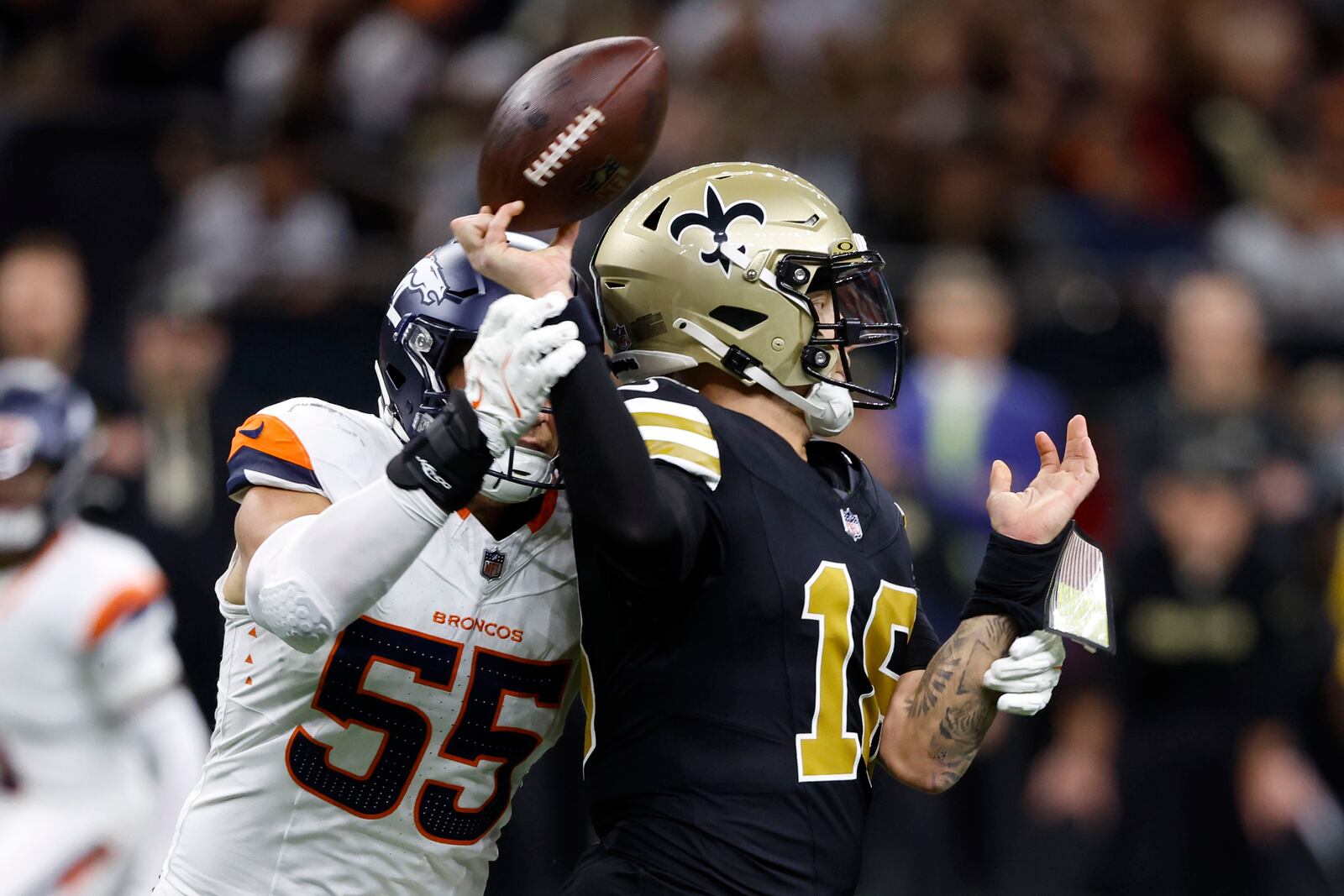 New Orleans Saints quarterback Spencer Rattler (18) fumbles the ball as he is hit by Denver Broncos linebacker Cody Barton (55) during the first half of an NFL football game, Thursday, Oct. 17, 2024, in New Orleans. The Broncos recovered the fumble. (AP Photo/Butch Dill)