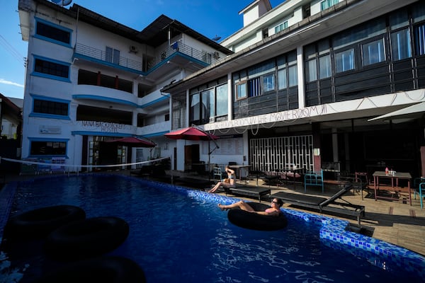 Foreign tourists relax at a swimming pool at Nana Backpack hostel in Vang Vieng, Laos, Tuesday, Nov. 19, 2024. (AP Photo/Anupam Nath)