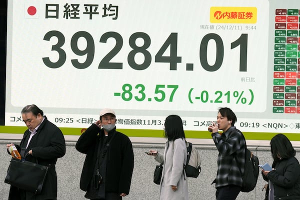 People stand in front of an electronic stock board showing Japan's Nikkei index at a securities firm Wednesday, Dec. 11, 2024, in Tokyo. (AP Photo/Eugene Hoshiko)