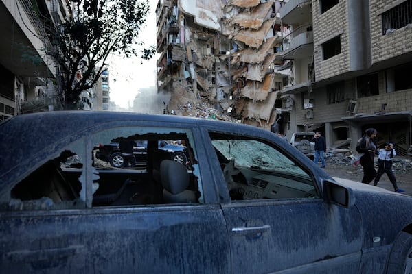 Residents pass in front of a destroyed building that was hit Sunday night in an Israeli airstrike in Dahiyeh, in the southern suburb of Beirut, Lebanon, Monday, Nov. 25, 2024. (AP Photo/Hussein Malla)