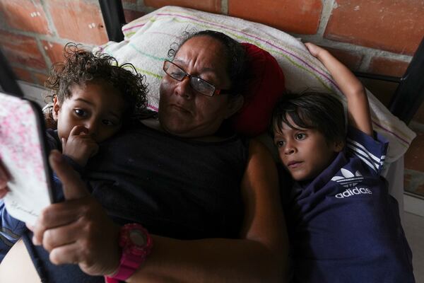 A Venezuelan woman and her grandchildren look at a cellphone at the Pope Francis Migrant Shelter in Palmira, Colombia, Friday, Nov. 1, 2024. (AP Photo/Juan Diaz)