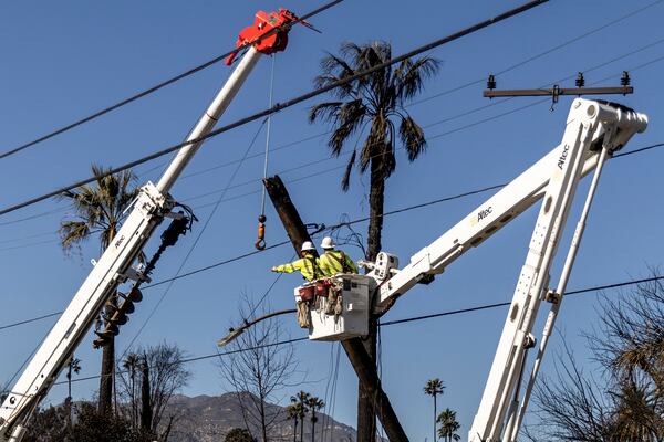 Workers with Southern California Edison remove a utility pole damaged by the Eaton Fire in Altadena, Calif., Sunday, Jan. 12, 2025. (Stephen Lam/San Francisco Chronicle via AP)