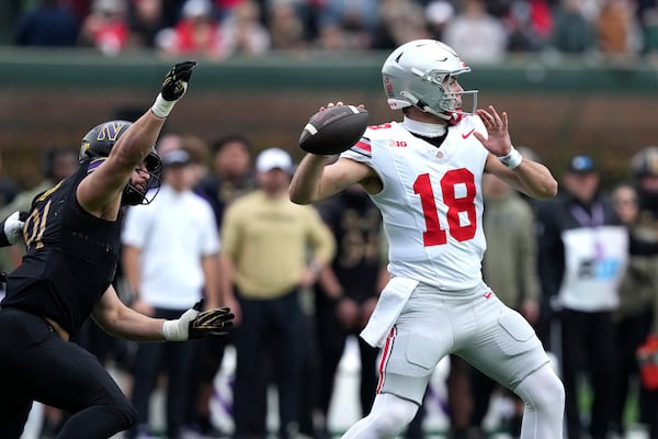 Ohio State quarterback Will Howard passes under pressure from Northwestern defensive lineman Aidan Hubbard during the first half of an NCAA college football game at Wrigley Field on Saturday, Nov. 16, 2024, in Chicago. (AP Photo/Charles Rex Arbogast)