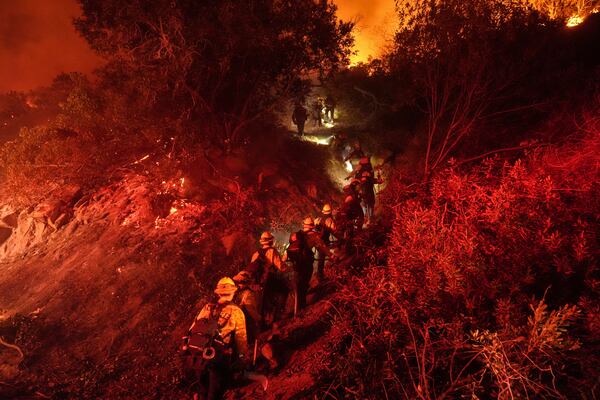 Firefighters walk up a ridge to battle the Lilac Fire in Bonsall, Calif., Tuesday, Jan. 21, 2025. (AP Photo/Jae C. Hong)