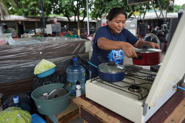 Maria Santos Garcia, 40, cooks for her family in a temporary shelter at the Suyapa neighborhood, partially flooded by the Ulúa River's overflow after Tropical Storm Sara, in Potrerillos, Honduras, Sunday, Nov. 17, 2024. (AP Photo/Moises Castillo)