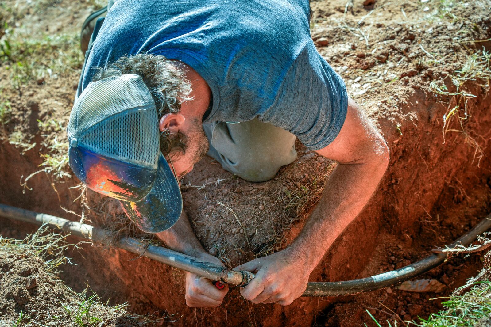 Jeffrey Martyn, a plumber and electrician works on a pipe fitting that draws water from a community well located on an urban farm that belongs to Bountiful Cities, a nonprofit organization, Monday, Oct. 14, 2024, in Asheville, N.C. (AP Photo/Kathy Kmonicek)