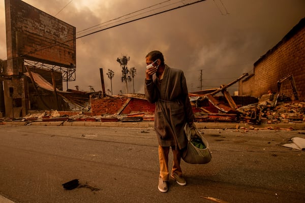 A man walks past a fire-ravaged business after the Eaton Fire swept through Wednesday, Jan. 8, 2025, in Altadena, Calif. (AP Photo/Ethan Swope)