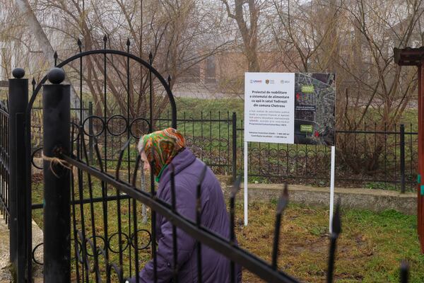 An elderly woman walks by a banner presenting a USAID supported project for the rehabilitation the water supply network in the village of Todiresti, Moldova, Thursday, Jan. 30, 2025. (AP Photo/Aurel Obreja)