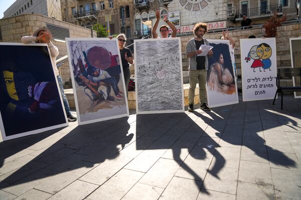 People hold boards during a protest against Israel's military operations in the Gaza Strip and Lebanon and calling for the release of hostages held in the Gaza Strip by the Hamas militant group, in Haifa, Israel, Friday, Nov. 22, 2024. Placard on the right reads “Children refuse to be enemies”. (AP Photo/Francisco Seco)