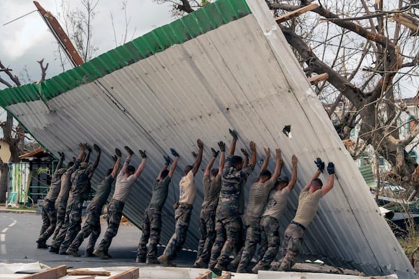 This photo provided by the French Army shows soldiers lifting a collapsed barrier in the Indian Ocean French territory of Mayotte, Wednesday Dec.18, 2024, as the cyclone on Saturday was the deadliest storm to strike the territory in nearly a century. (D Piatacrrea, Etat Major des Armees/Legion Etrangere via AP)